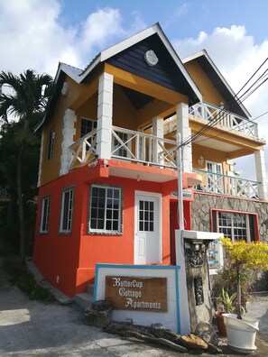 A multi-story building with a sign reading "ButterCup Cottage Apartments." - Buttercup Cottage Apartments (Arnos Vale)