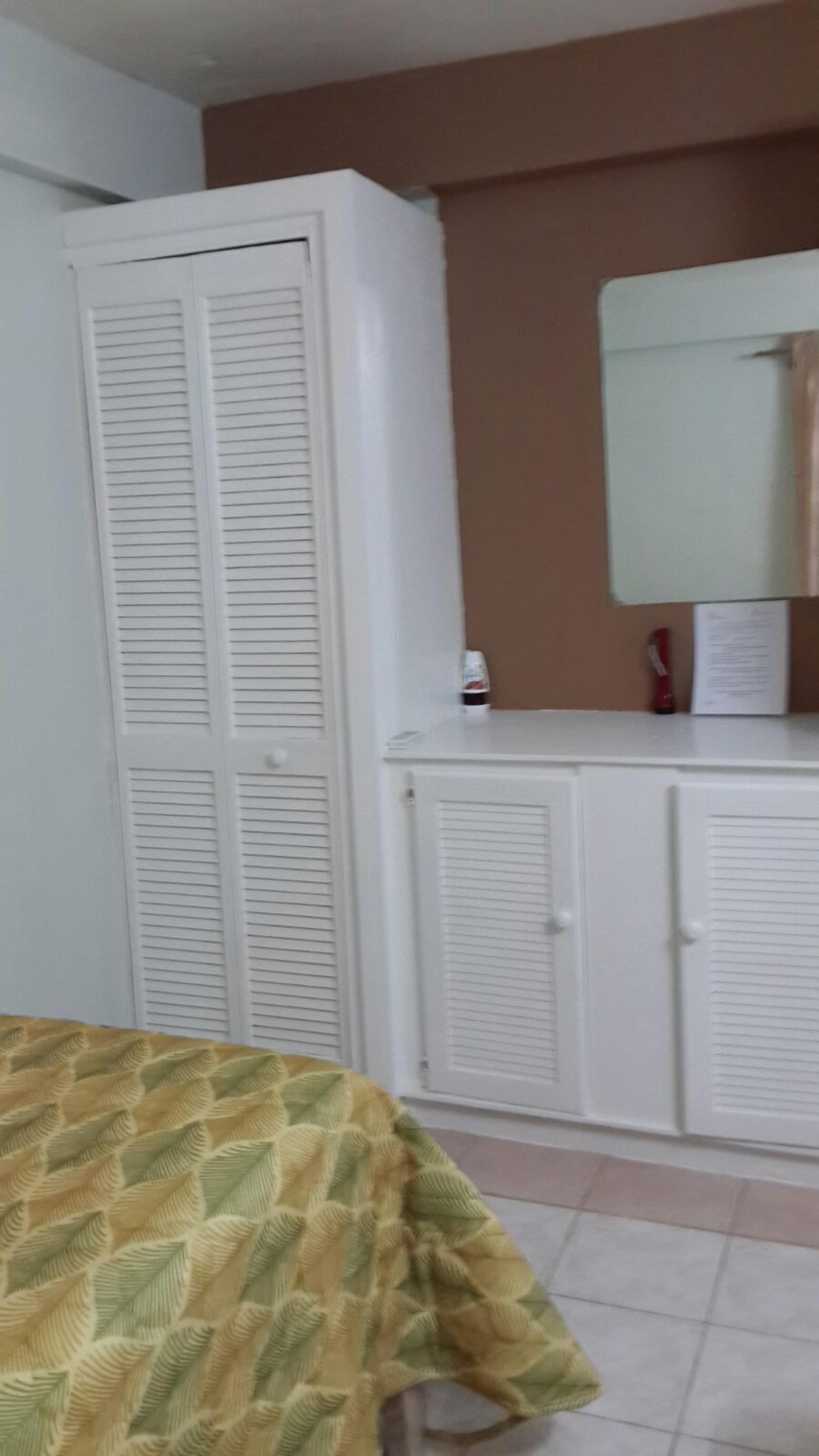 A room with a bed, a wardrobe, and a mirror.