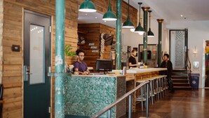 A modern bar area with wooden walls, green pendant lights, and a counter with a mosaic tile design. - The Quisby Hotel (New Orleans)