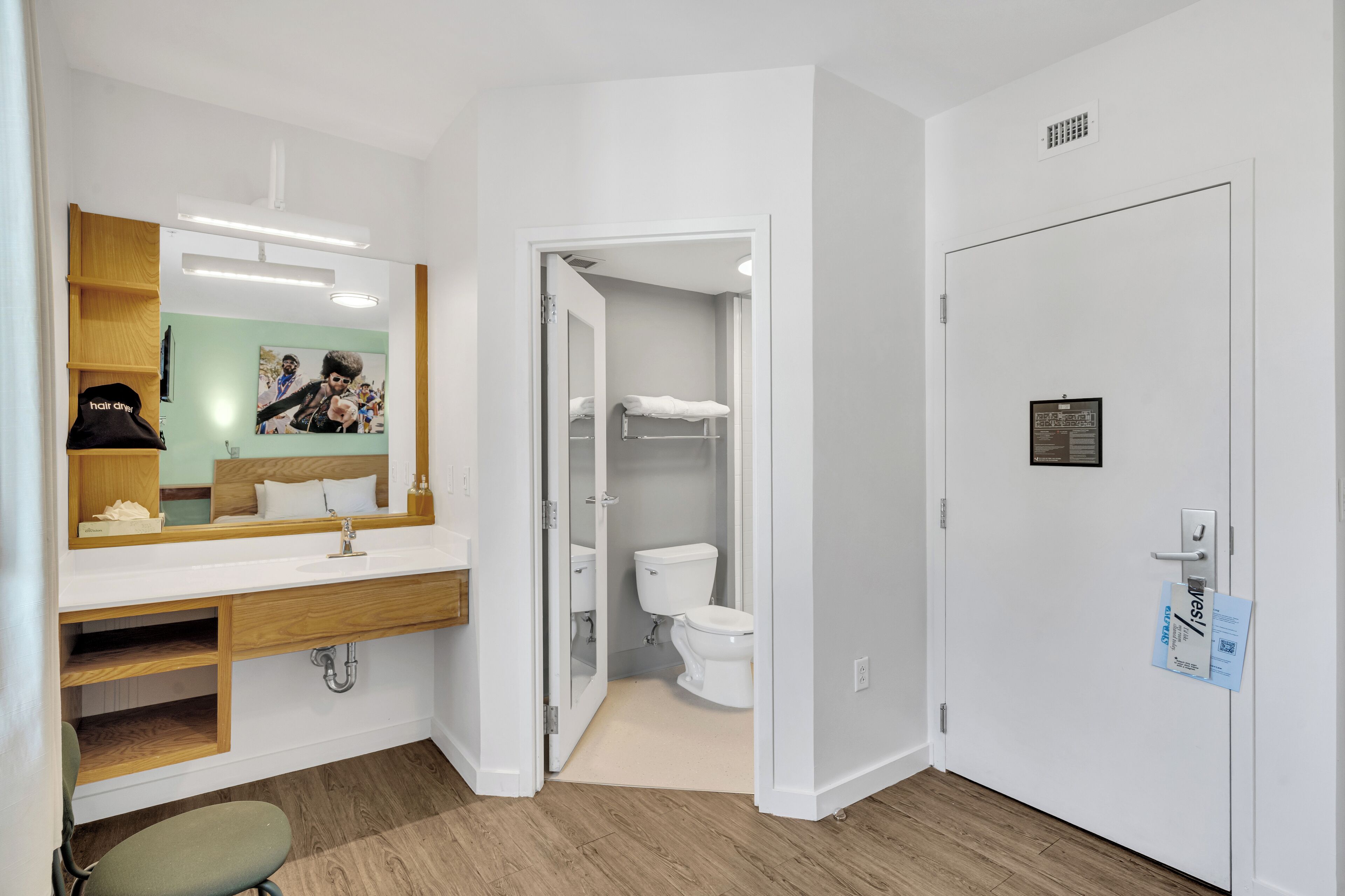 A modern bathroom with a wooden vanity, a mirror, a toilet, and a shower area.