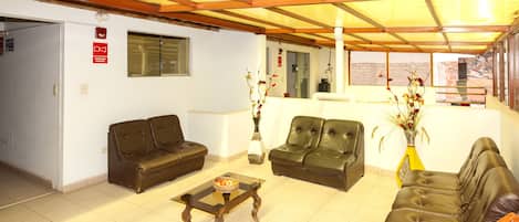 A hotel lobby with leather sofas, a wooden coffee table, and a vase with flowers.