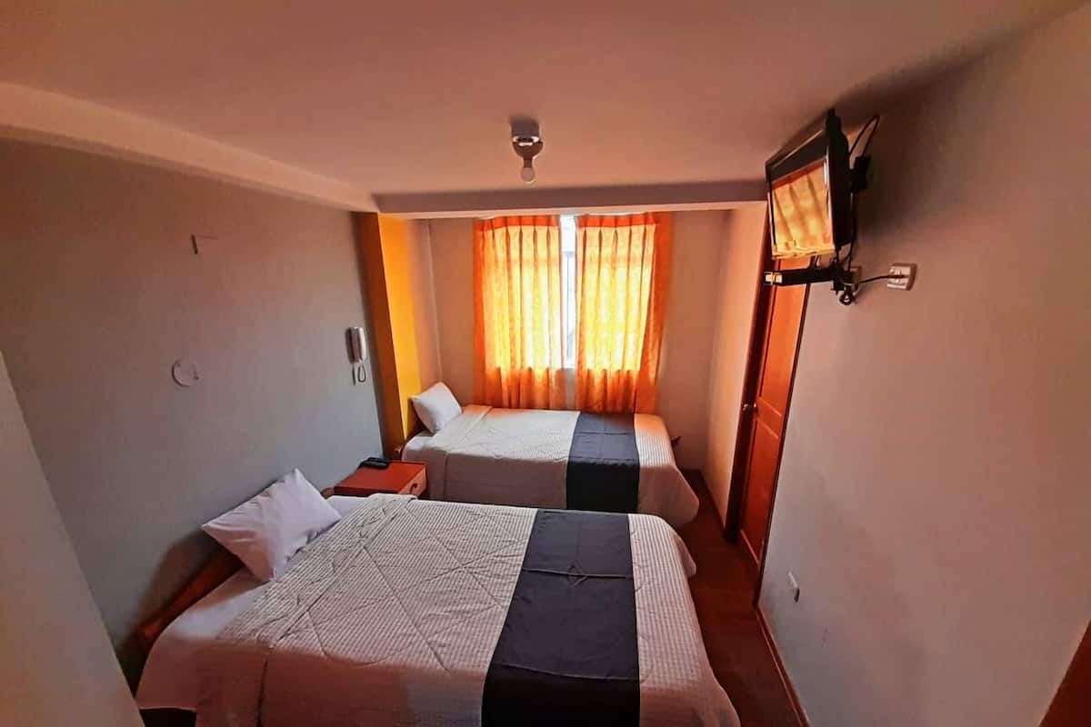 Une chambre avec deux lits, un ventilateur de plafond et une fenêtre avec des rideaux.