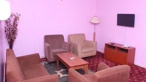 Una stanza con una parete rosa, un armadietto in legno, una televisione e due sedie.