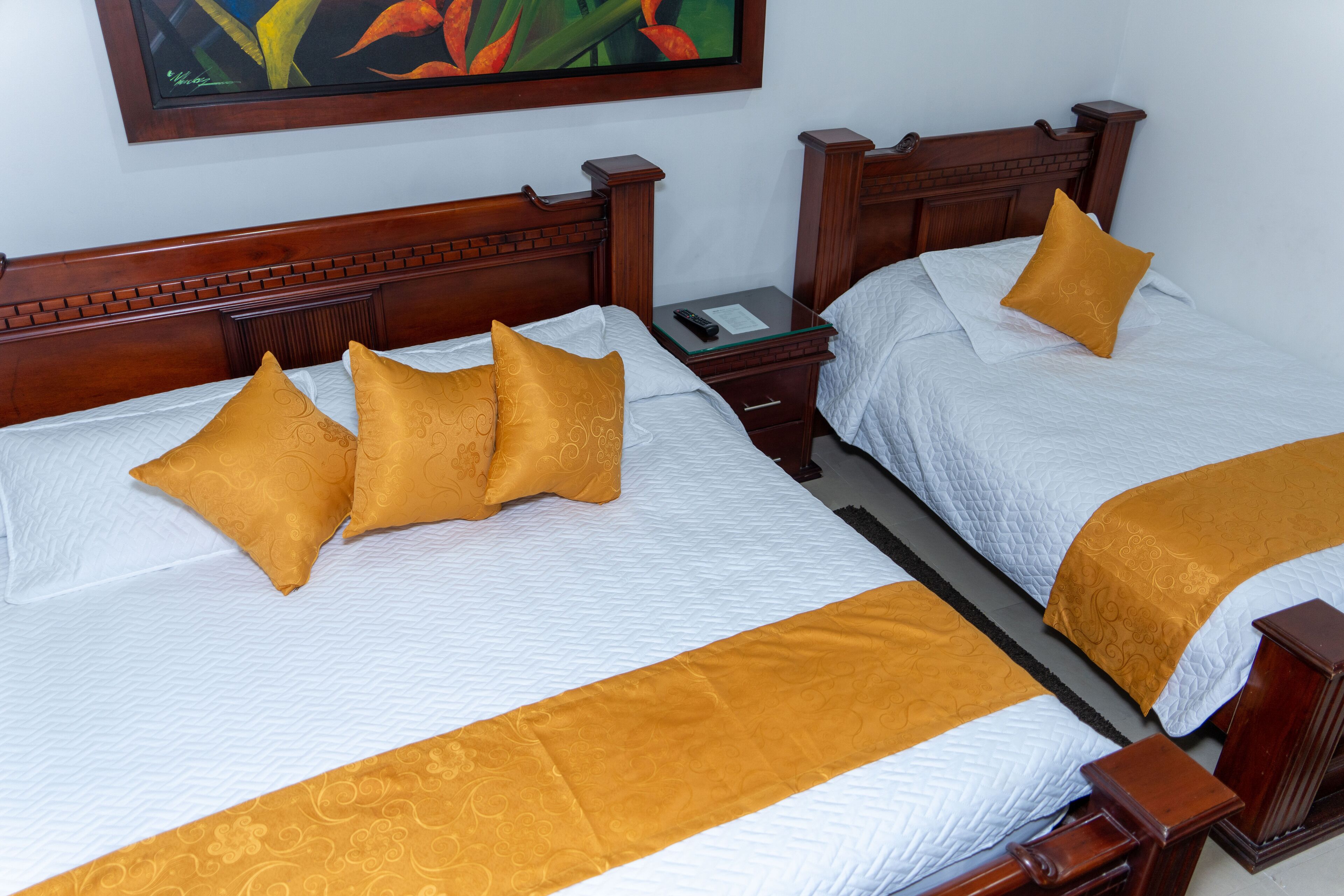 Two double beds with wooden headboards, white bedding, and gold accents.