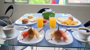 A breakfast table with plates of food, glasses of orange juice, and cups of coffee. - Hotel Aires Del Quindio (Armenia)