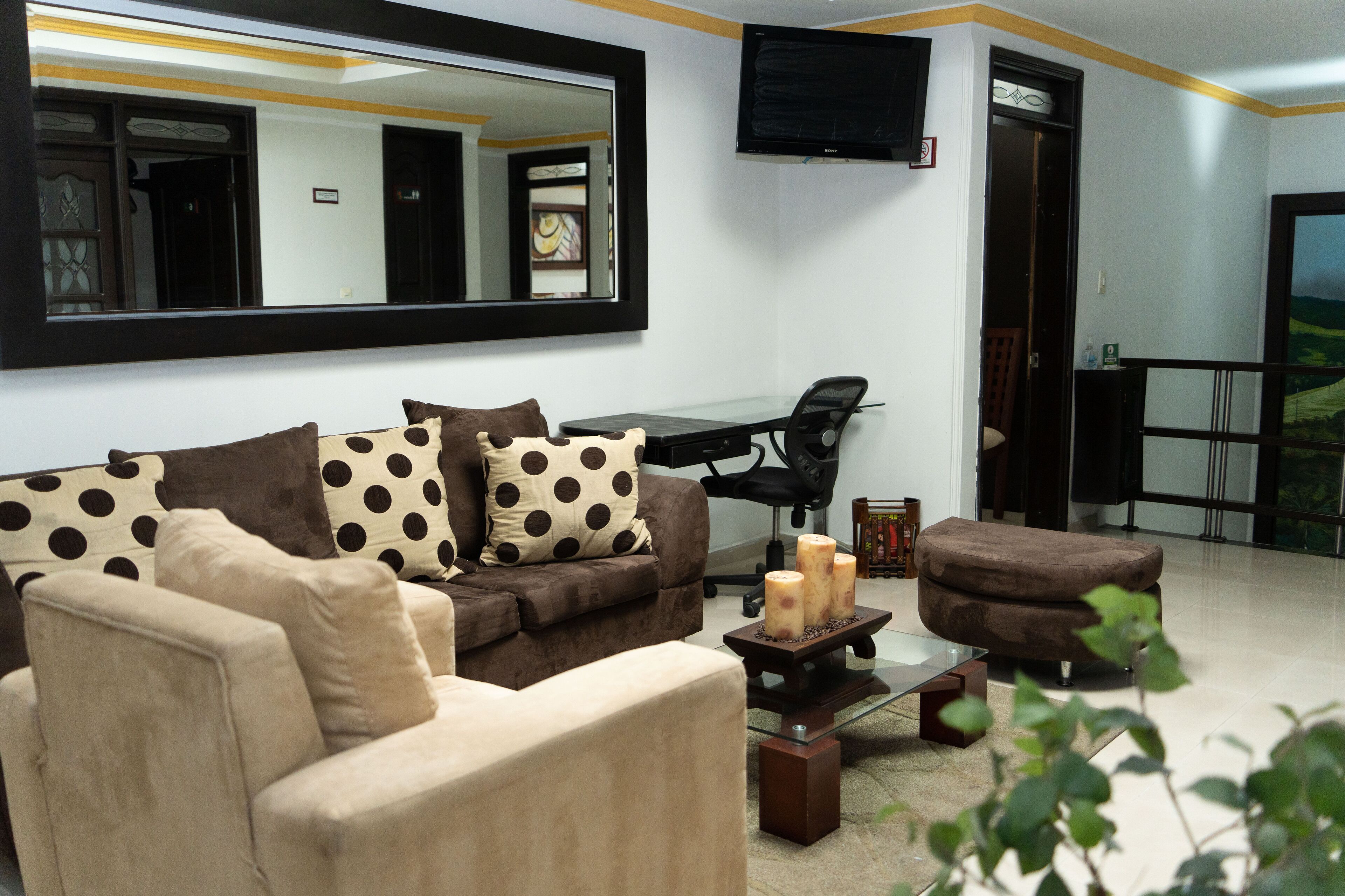 A living room with a sofa, armchair, coffee table, and a large mirror.