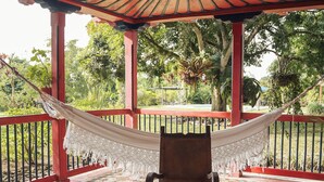 A covered patio with a hammock, chairs, and a table with a decorative centerpiece. - Finca Cafetera El Balso (Armenia)