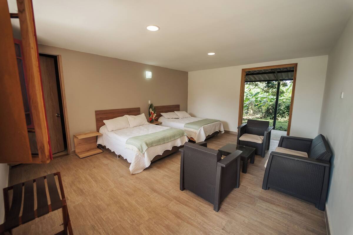 Una habitación con dos camas, una mesita y una silla.