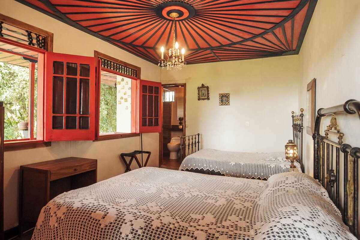 Un dormitorio con una cama grande, un escritorio de madera y una ventana con persianas rojas.