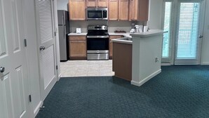 A modern kitchen with wooden cabinets, stainless steel appliances, and a small island. - Vacation Village at Williamsburg (Williamsburg)
