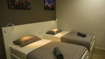 A hotel room with two beds, a headboard, a wall-mounted picture, and a ceiling light.