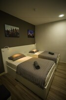 A hotel room with two beds, a headboard, a wall-mounted picture, and a ceiling light.