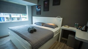 Una habitación de hotel moderna con cama, escritorio y una pequeña kitchenette.