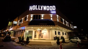 Un edificio con un llamativo letrero que dice 'HOLLYWOOD HOTEL', que presenta un diseño moderno con techo plano y múltiples ventanas.
