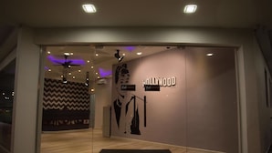 Entrada moderna de hotel con un letrero de 'Hollywood', felpudo y una pared con diseño de tablero de ajedrez.