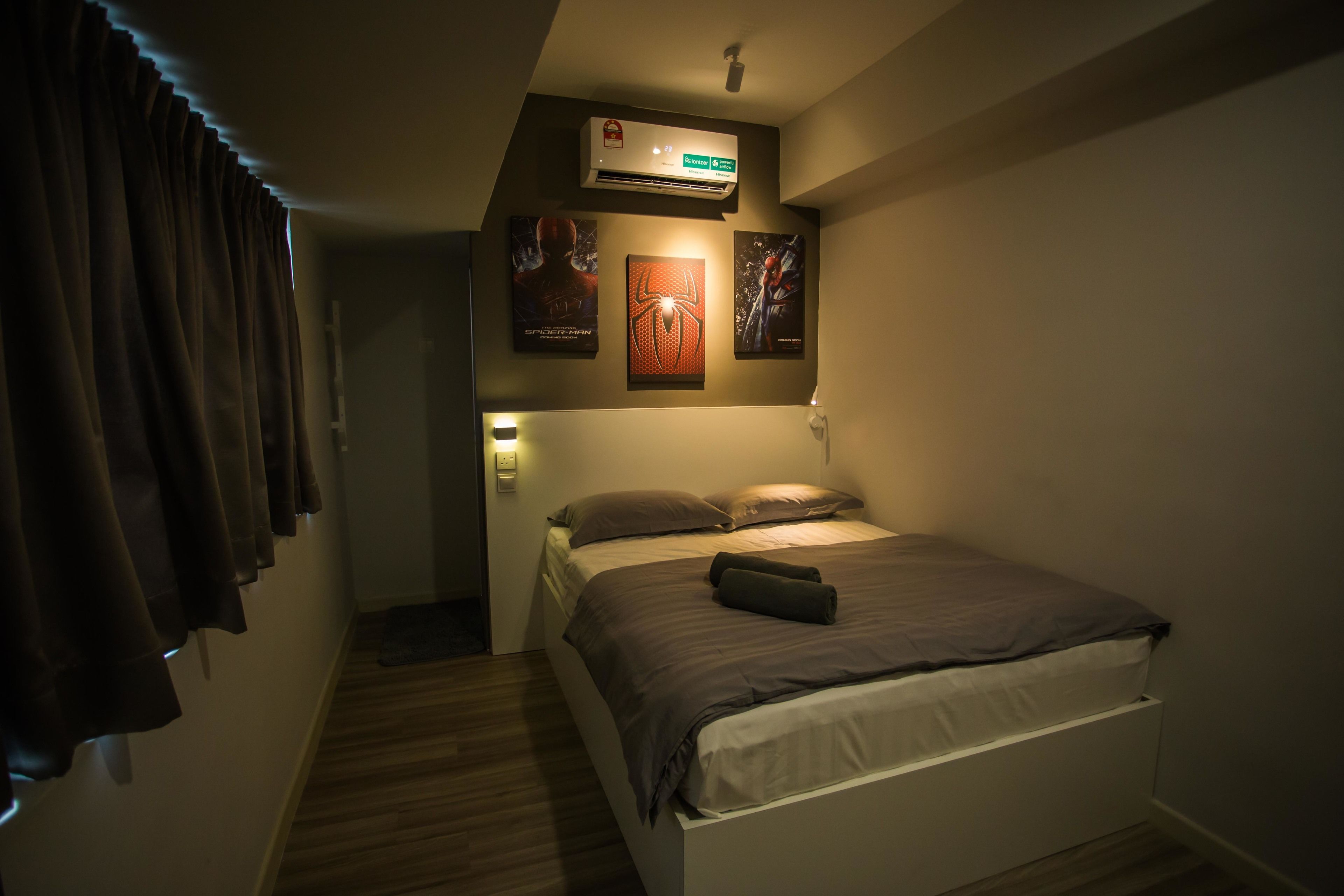 Un dormitorio con cama, aire acondicionado de pared y carteles enmarcados.