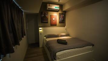 Un dormitorio con cama, aire acondicionado de pared y carteles enmarcados.