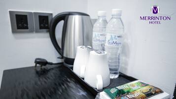 Una habitación de hotel con cafetera, dos botellas de agua, un cápsula de café y una bandeja.