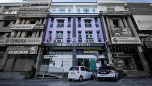 A hotel with multiple business signs, including 'Merrinton Hotel' prominently displayed. - Merrinton Hotel (Temerloh)