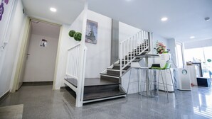 A modern hotel lobby with a staircase, a reception desk, and a view of the Eiffel Tower. - Merrinton Hotel (Temerloh)