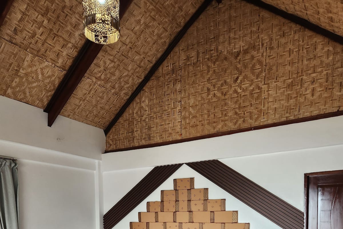 Um quarto com uma cama de madeira, uma mesa de cabeceira, uma luminária e uma porta.