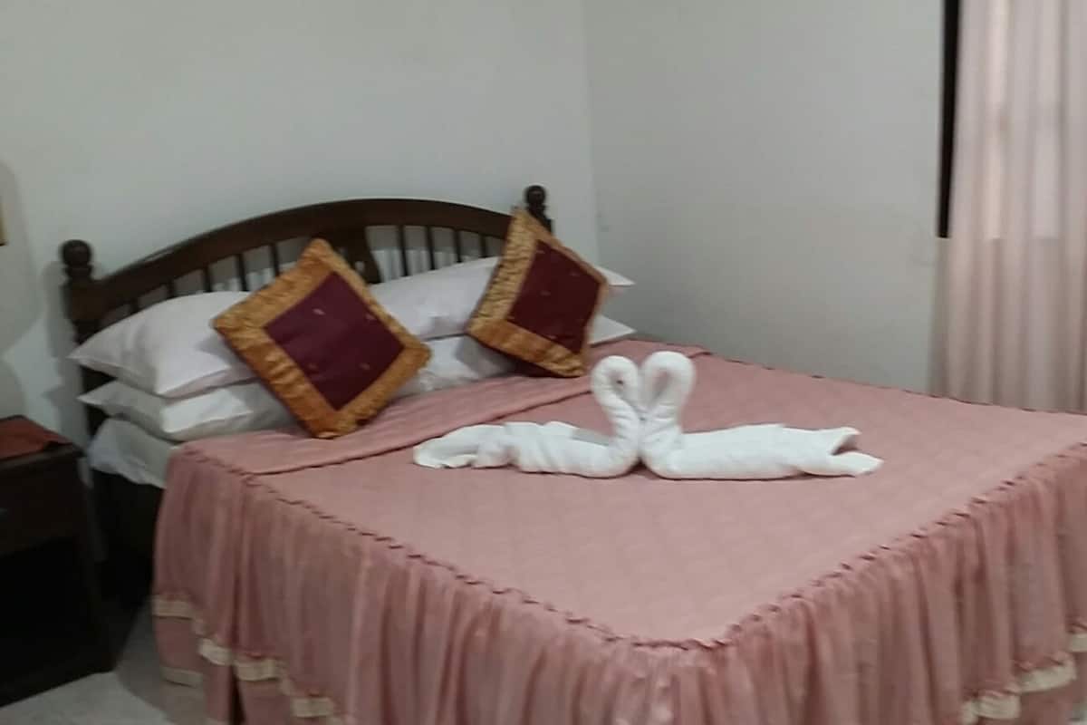 Uma cama com um edredom rosa e duas almofadas decorativas.