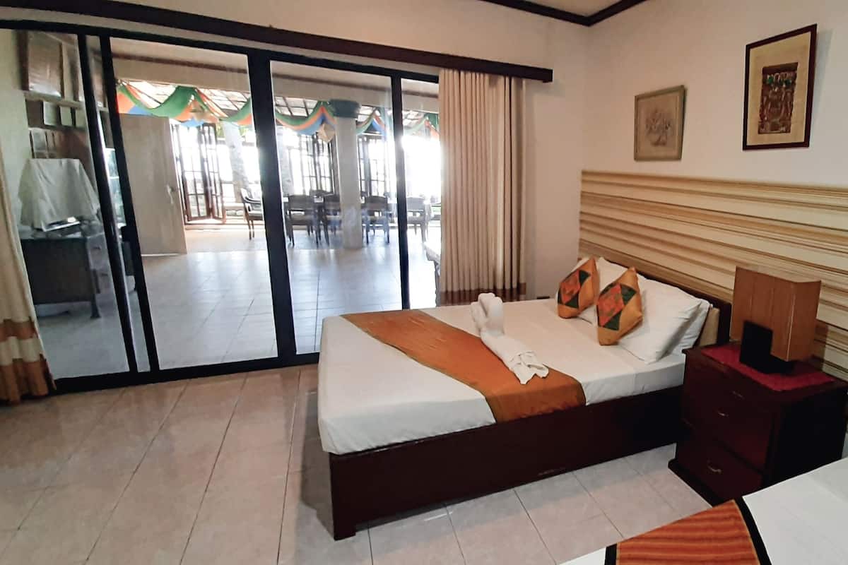 Quarto de hotel com cama, mesa de cabeceira, espelho e vista para a área externa.