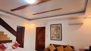 A bedroom with a bed, a sofa, a coffee table, and a staircase. - Brazaville Beach Resort (Hinoba-an)