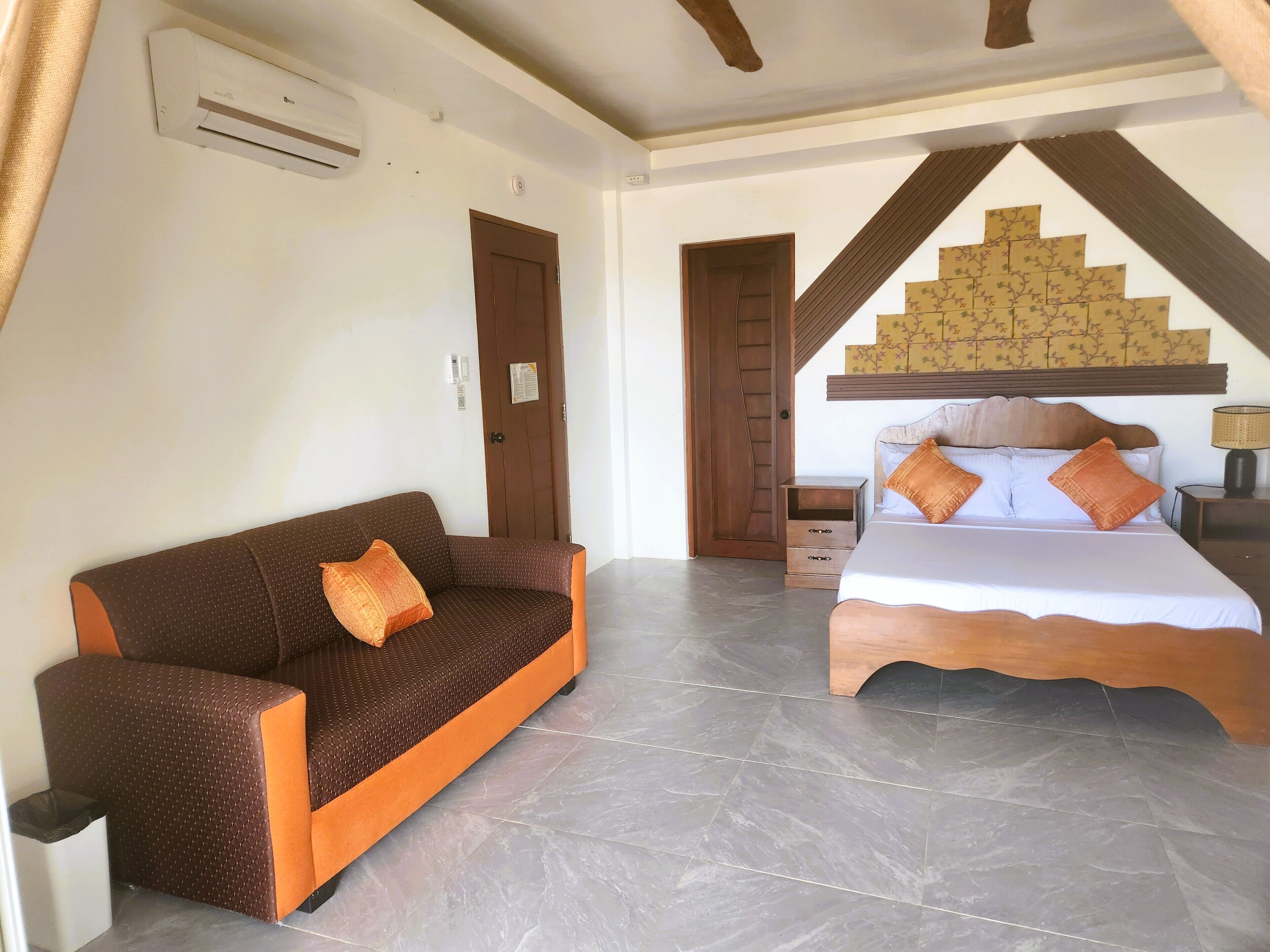 Un dormitorio con cama, sofá, mesita de noche y aire acondicionado instalado en la pared.