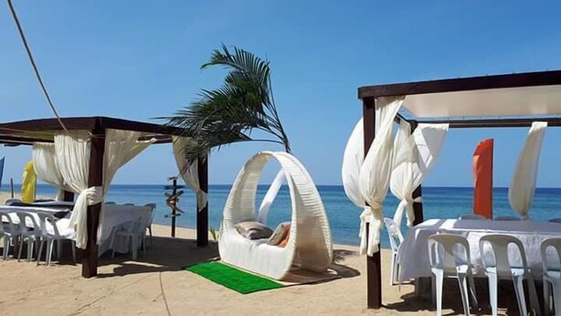 A beachside setting with white canopies, a hanging chair, and a table with chairs. - Brazaville Beach Resort (Hinoba-an)