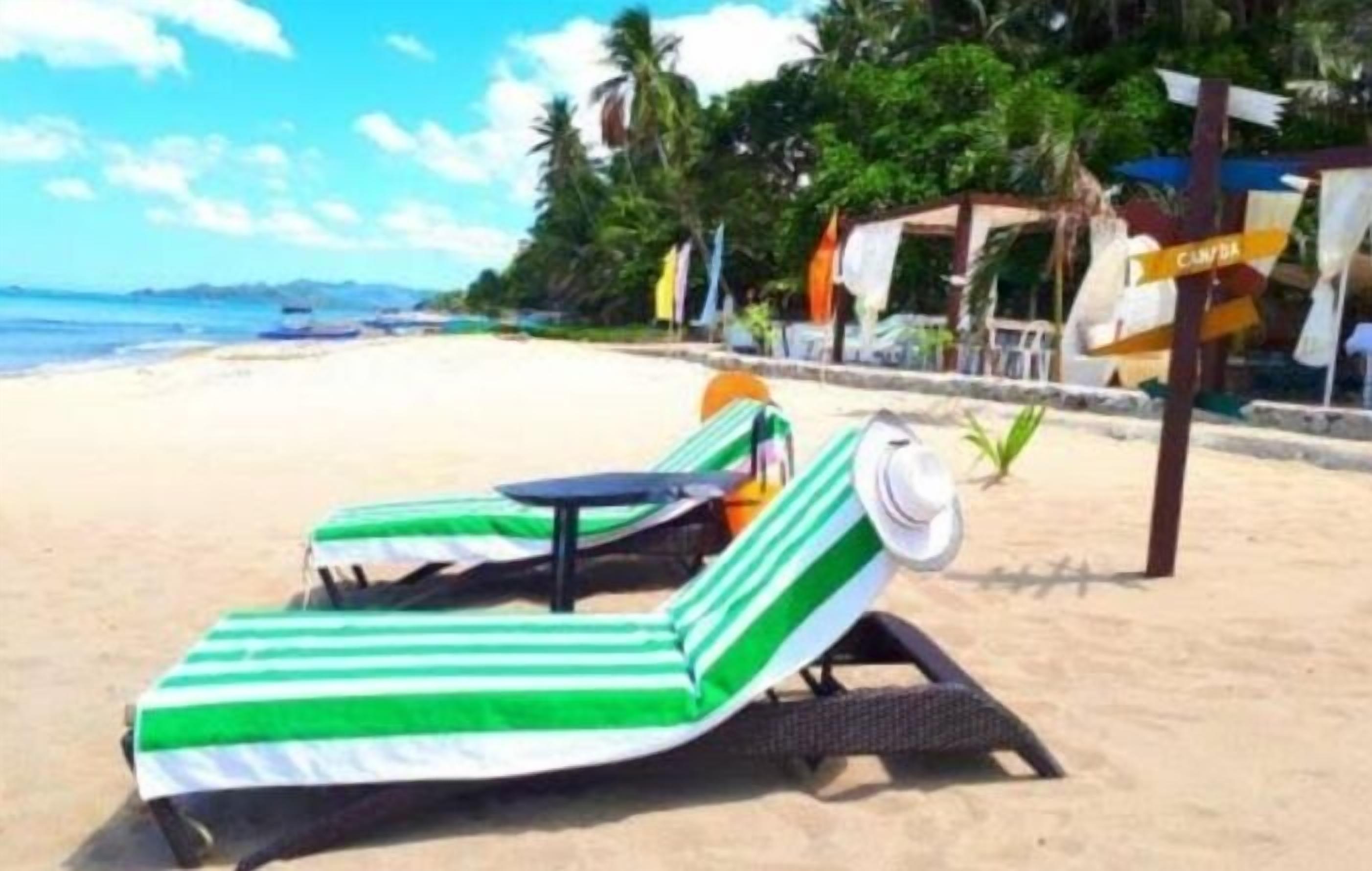 Une plage avec un transat et un panneau indicateur.