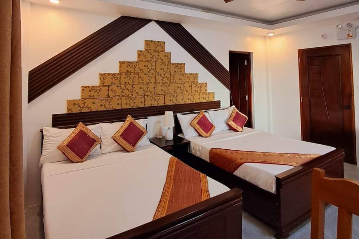 Quarto de hotel com cama, escrivaninha e um objeto decorativo fixado na parede.