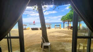 A beach view from a covered area with a concrete floor, a single plastic chair, and a small table. - Brazaville Beach Resort (Hinoba-an)