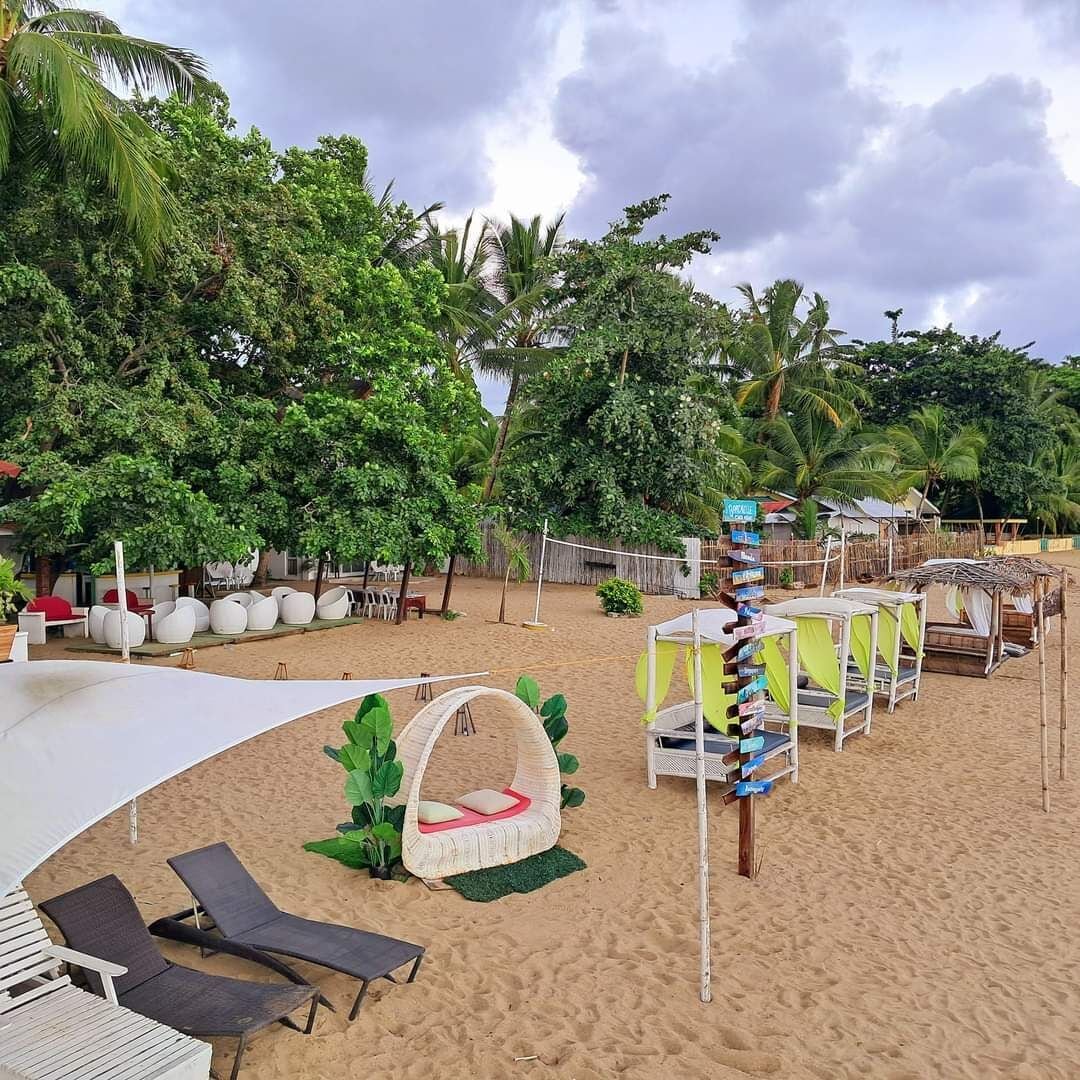 Un resort frente a la playa con sillas de descanso, una pérgola y una zona cubierta.