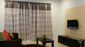 Una sala de estar con sofá, otoman, mesa de centro y televisor montado en la pared.