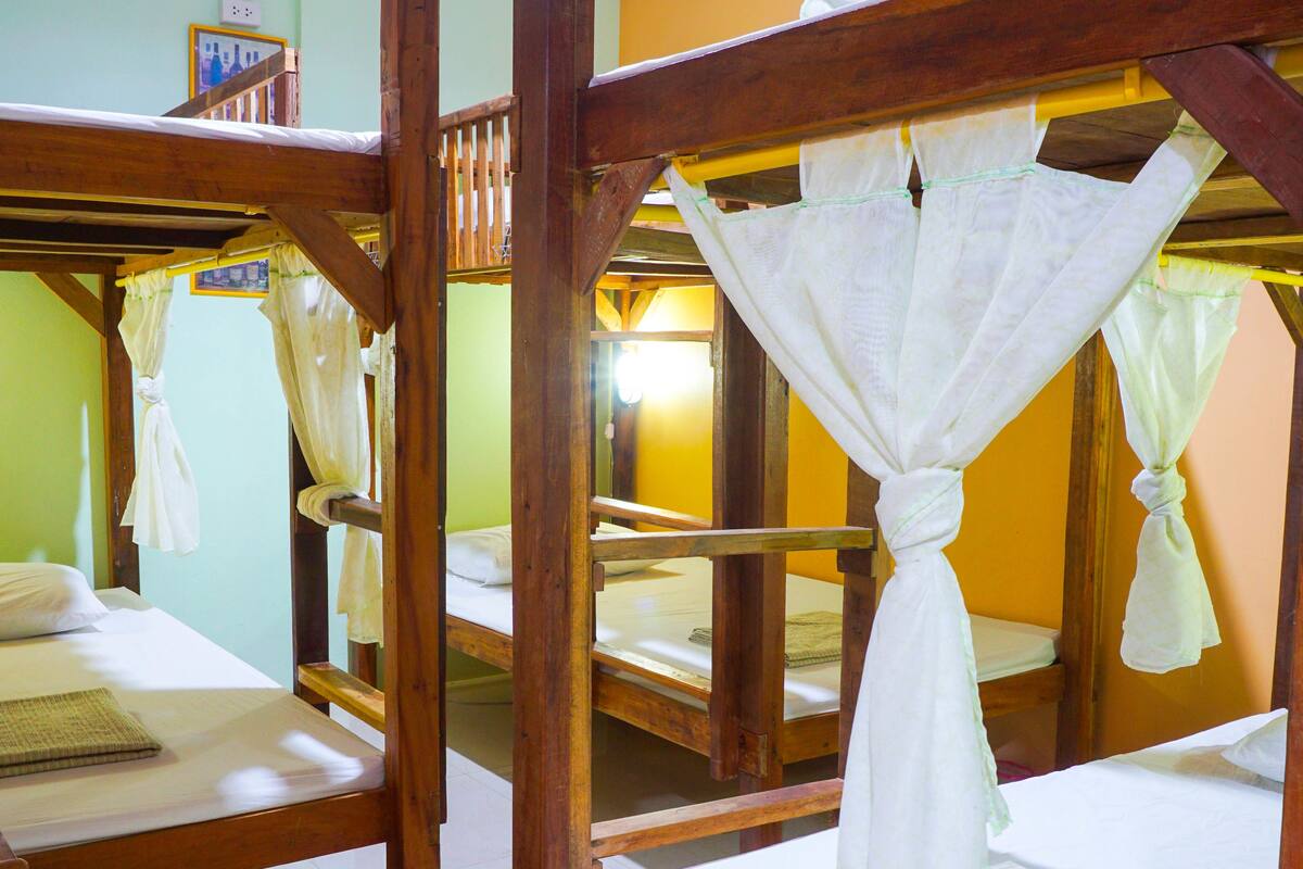 A room with bunk beds, each with a mosquito net.