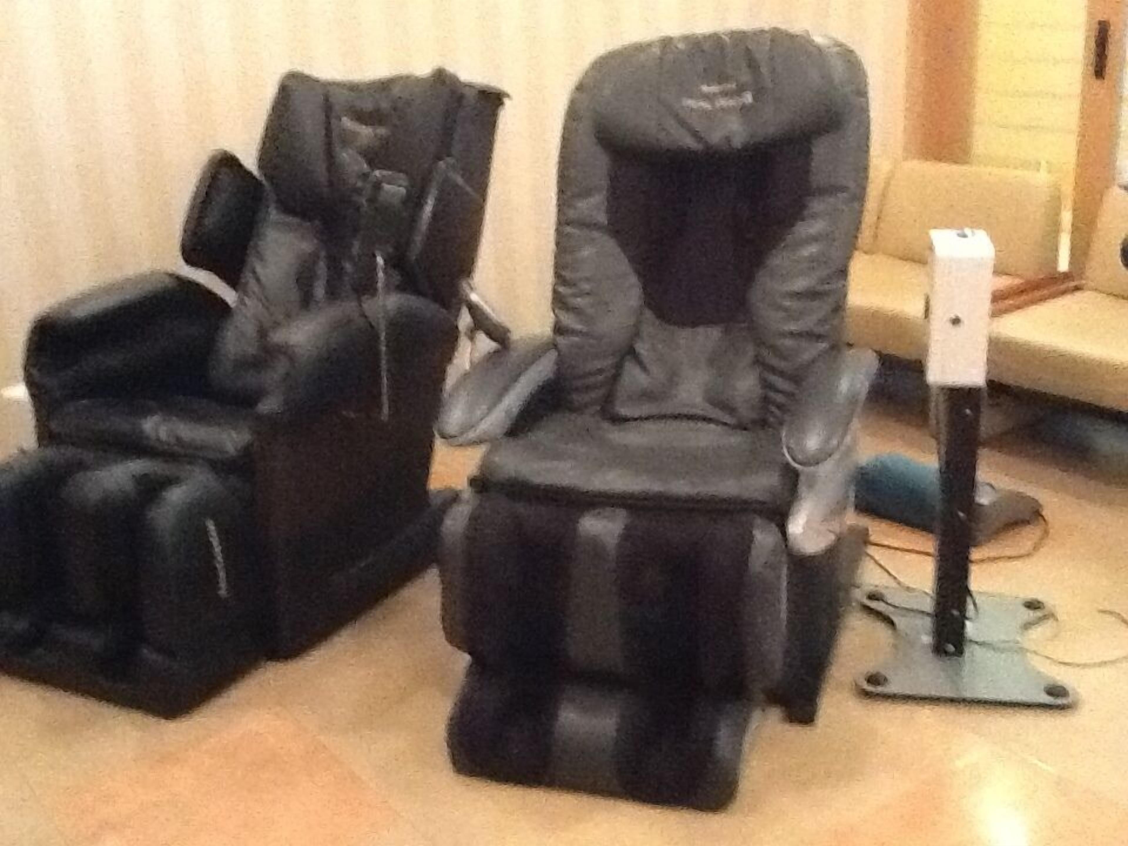 A massage chair in a room with a beige sofa and a small table.
