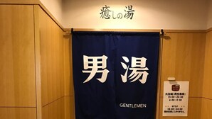 Baño de hombres con un letrero sobre la puerta que dice "Gentlemen" y un letrero más pequeño con el horario de atención.