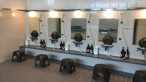 Un baño público con varios lavamanos, espejos y taburetes.