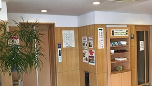 Un área de recepción con una planta en maceta, paneles de madera, un tablón de anuncios y una máquina expendedora.