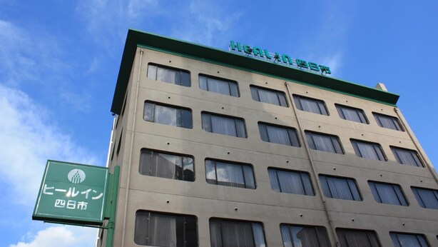 Un edificio de varios pisos con techo verde y un letrero que indica que es un hotel en Hiroshima.