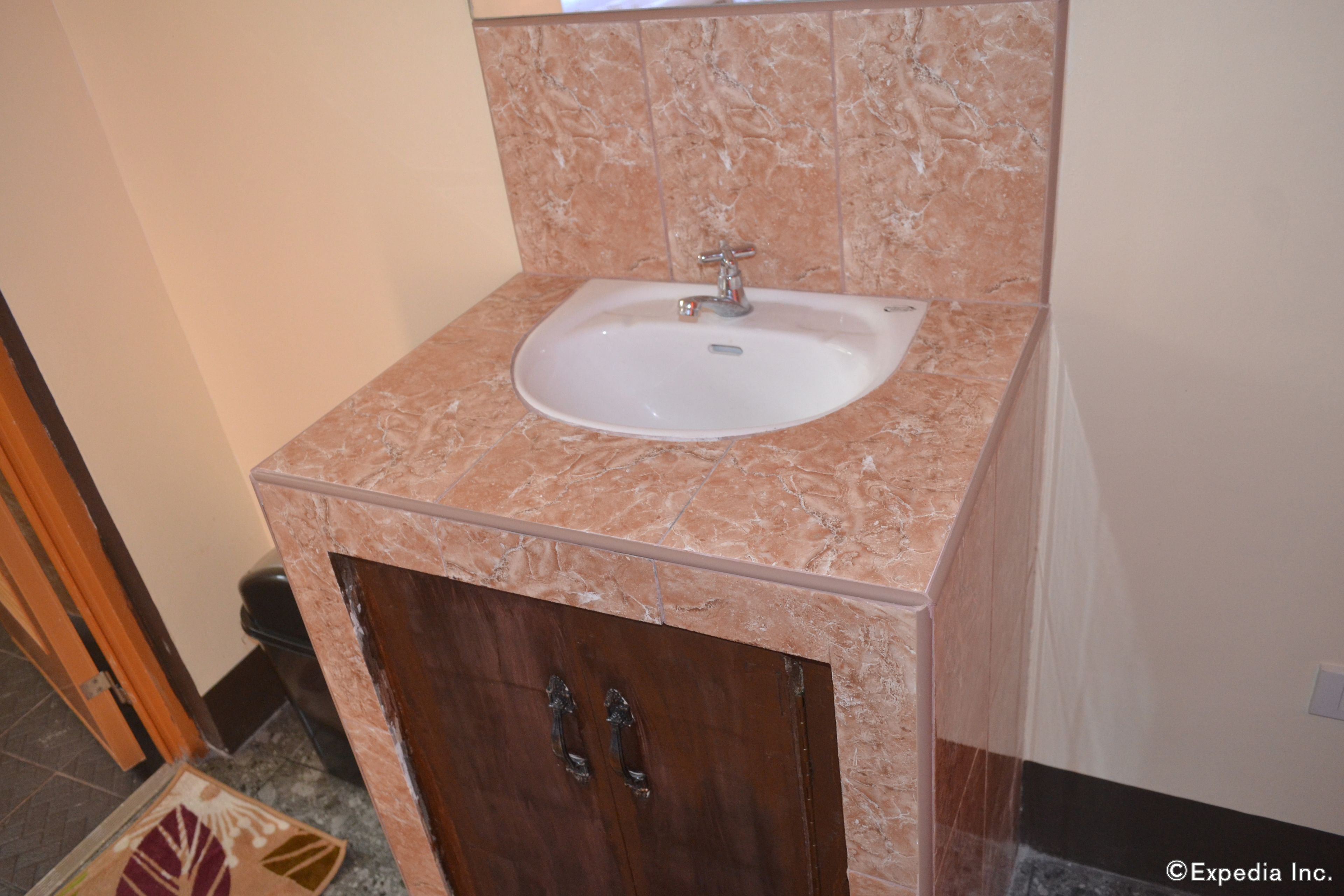 A bathroom with a marble sink, wooden cabinet, and a tiled floor.