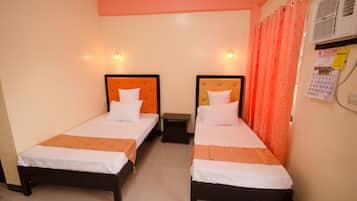 A hotel room with two single beds, each with a headboard, a nightstand, and a wall-mounted air conditioning unit.
