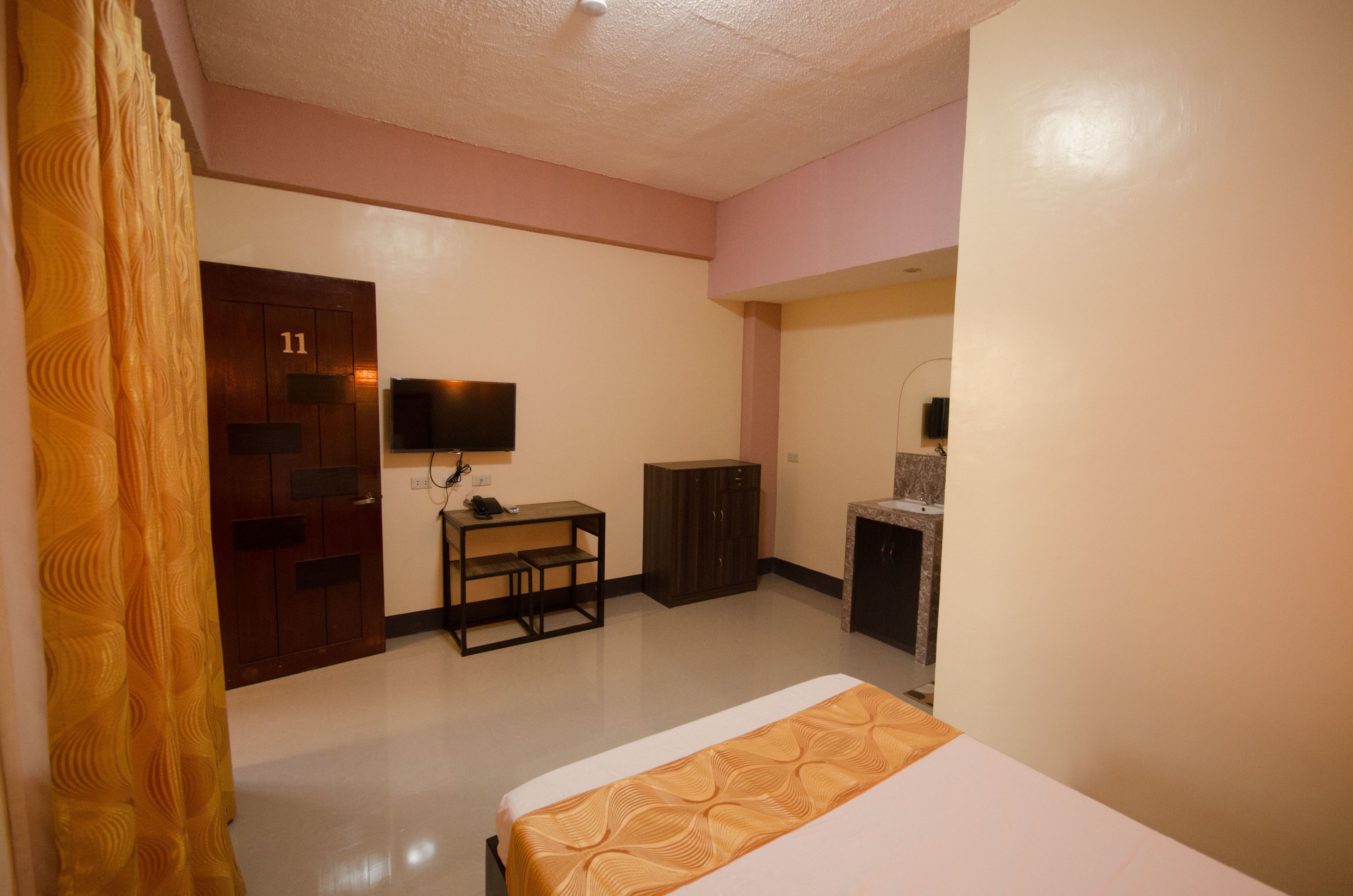 A hotel room with a bed, a desk, a television, and a wardrobe.