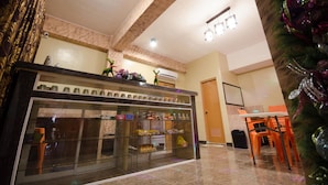Hall d'albergo con teca in vetro piena di snack, una reception e un albero di Natale.