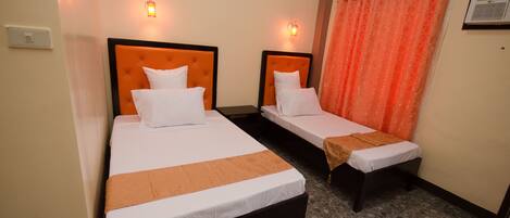 A hotel room with two single beds, each with a headboard and a bedside table.