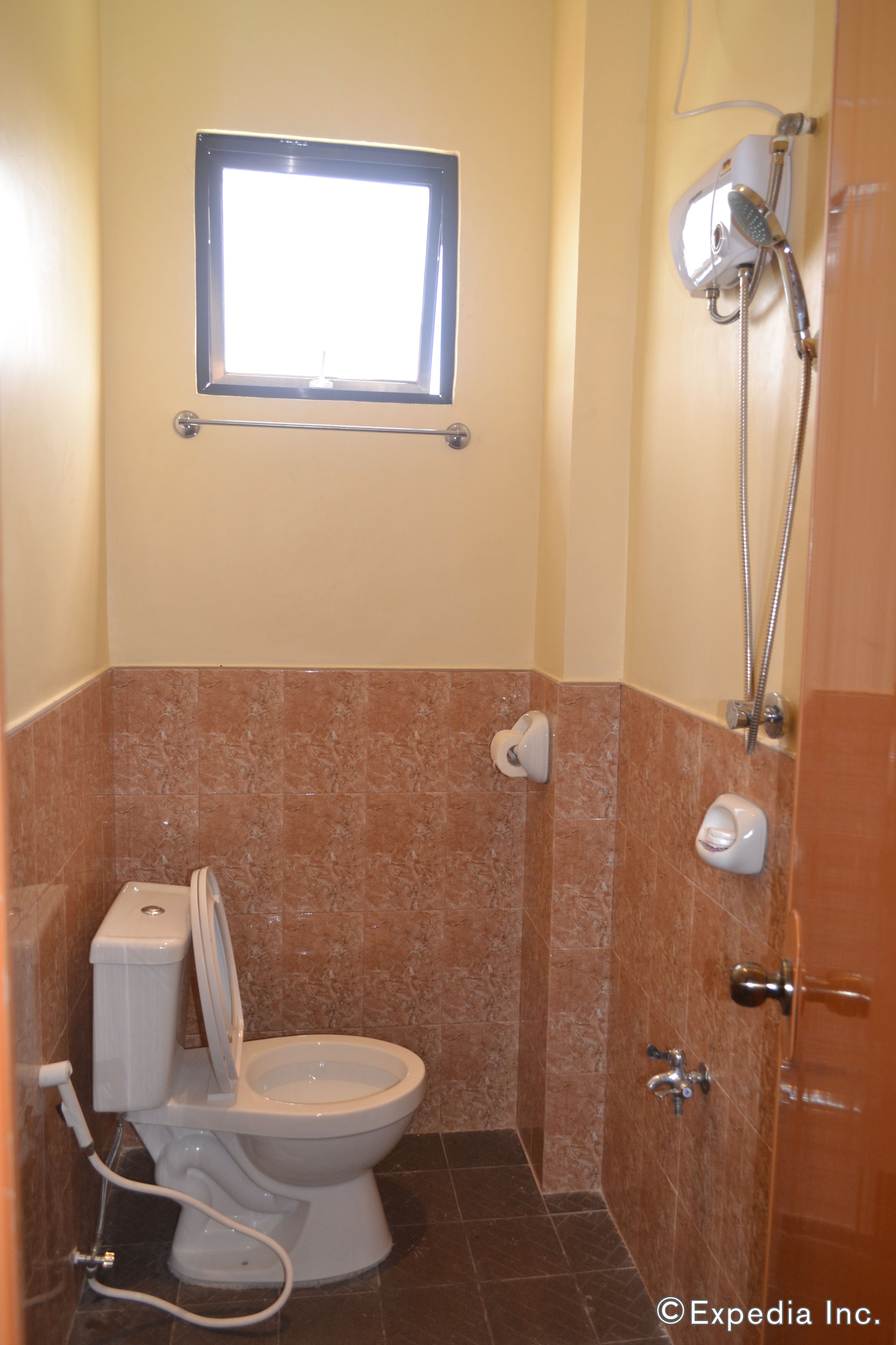 A bathroom with a toilet, a shower, and a window.