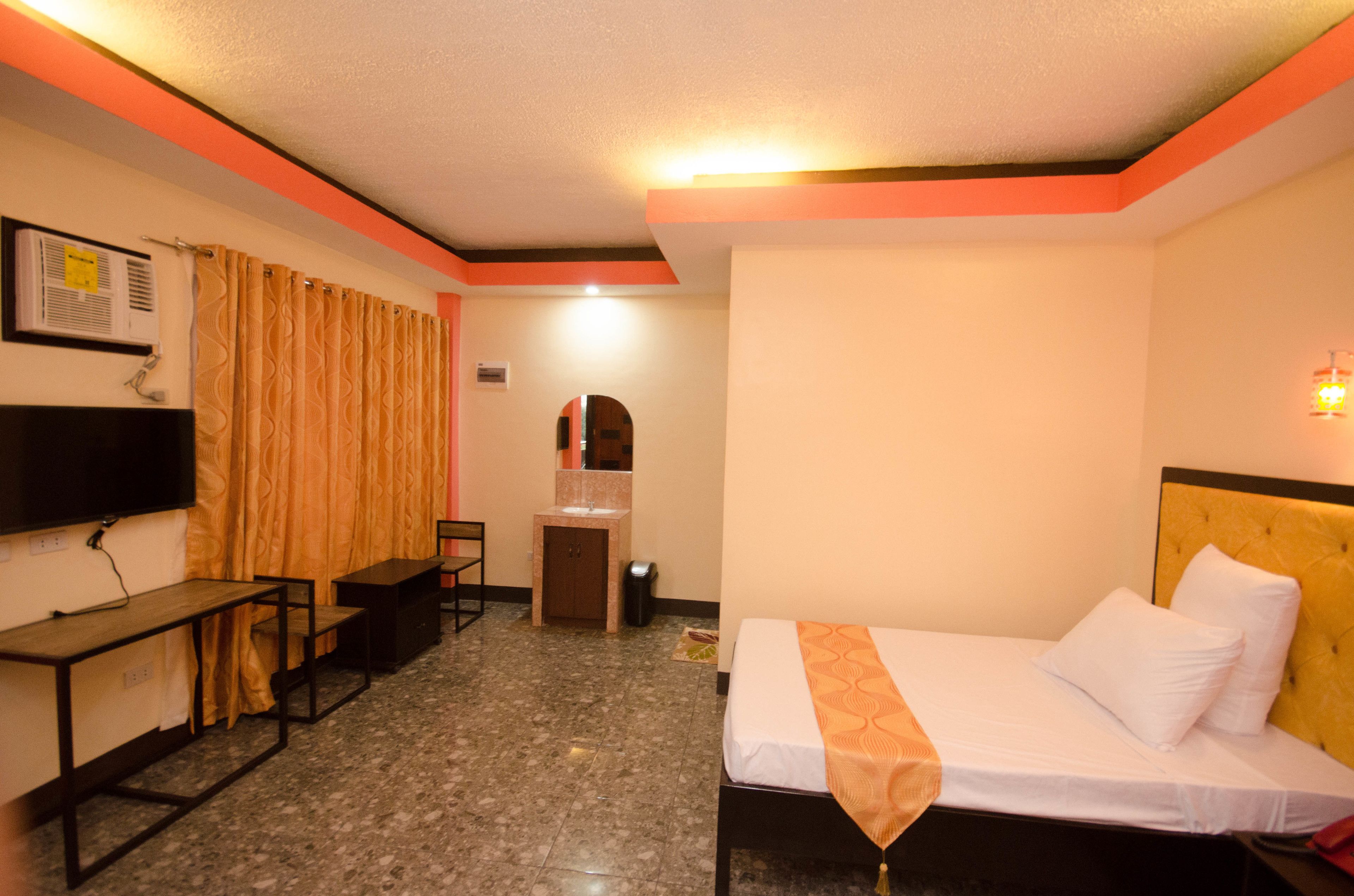 A hotel room with a bed, desk, chair, and a small bathroom area.