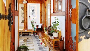 Un interior de madera tradicional con suelo de piedra, bancos de madera y plantas en macetas.