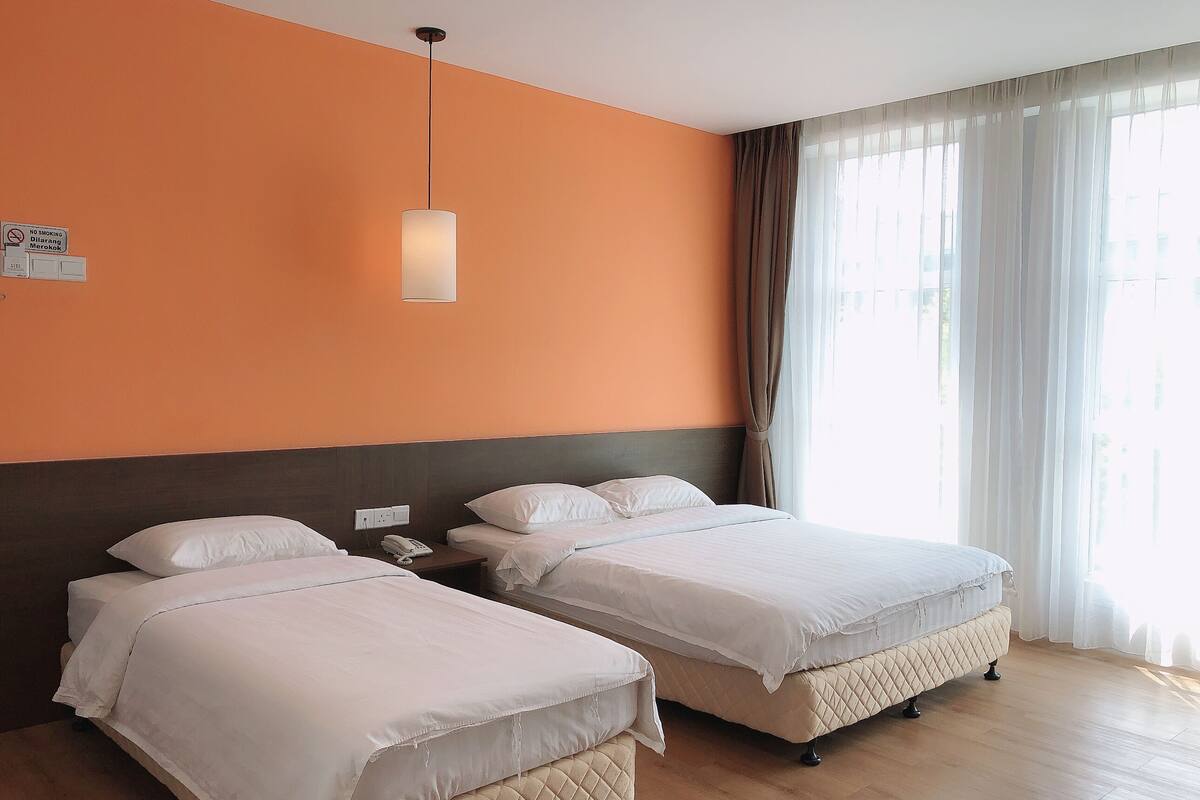 A hotel room with two beds, a telephone, and a light fixture.